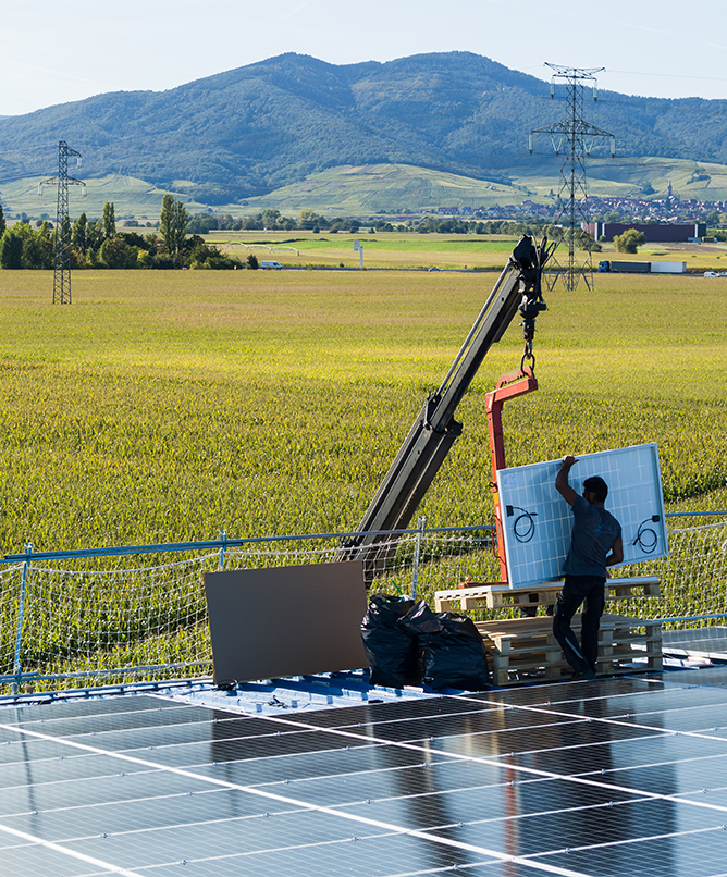 Un installateur décharge et pose un module photovoltaïque.